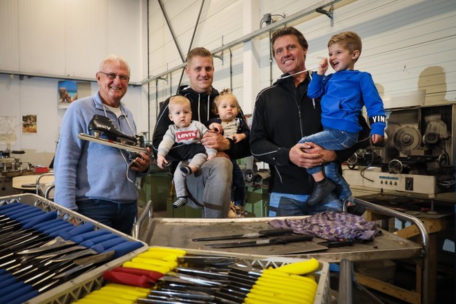 Drie generaties met jonge kinderen in de werkplaats, voor bakken vol geslepen messen